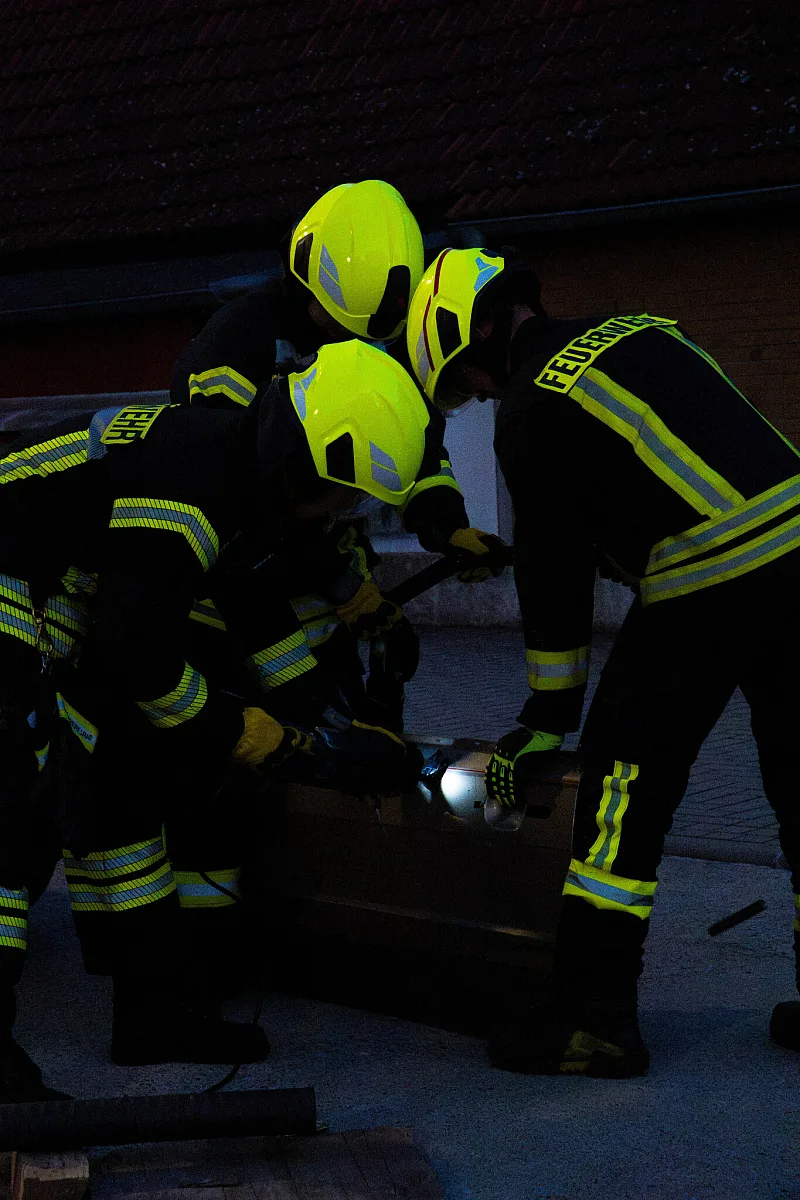 Drei Feuerwehrleute arbeiten gemeinsam am Übungsobjekt