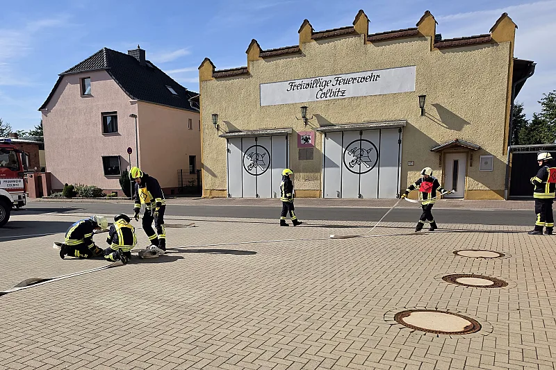 Einsatzkräfte kuppeln Schläuche auf dem Hof vor dem Gebäude der Freiwilligen Feuerwehr Colbitz